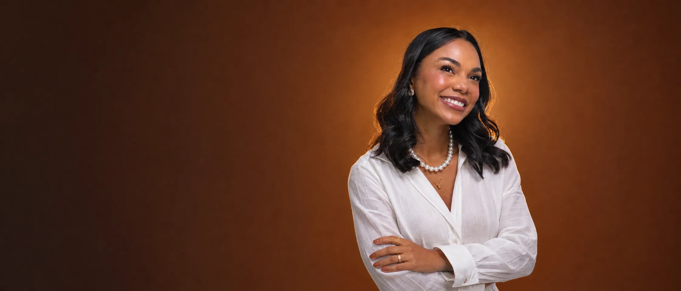 Dra. Laynna Lima, cirurgiã-dentista e mestre em Implantodontia, sorrindo de braços cruzados
